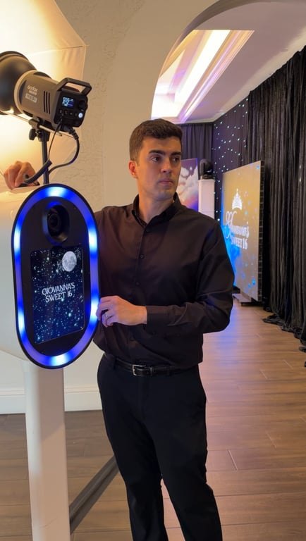 Gabe standing beside a photo booth with a glowing blue ring light