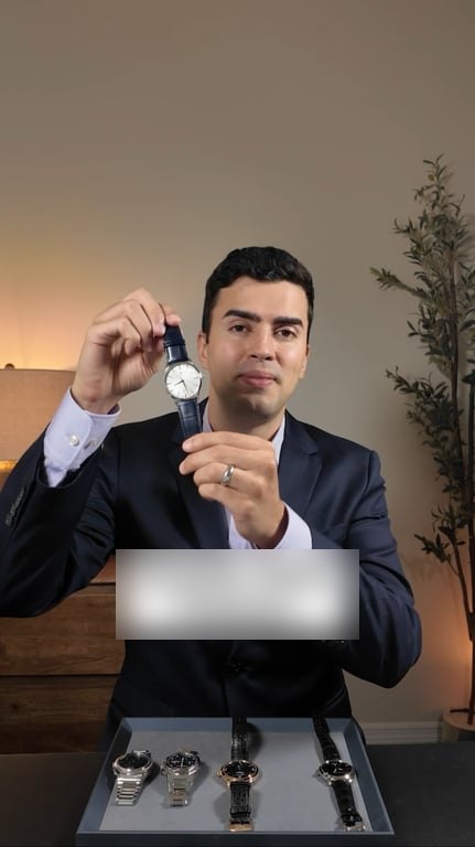Gabe in a suit holding up a wristwatch to the camera